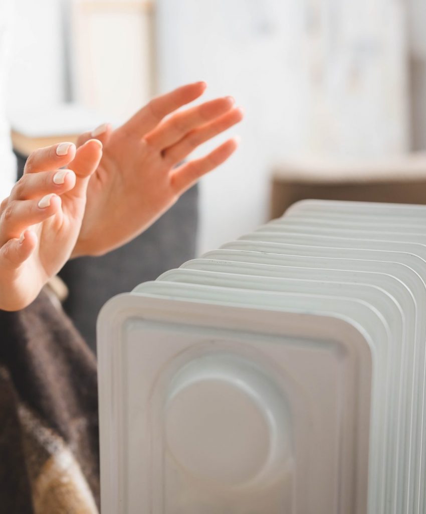 partial view of girl warming up with heater in cold room partial view of girl warming up with heater in cold room